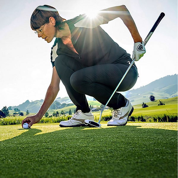 Golfspielerin legt Golfball aufs Grün